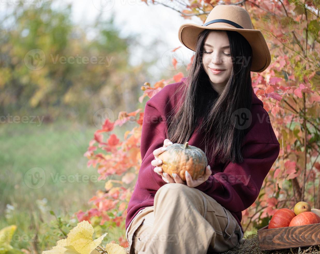 Happy young girl with pumpkin in autumn garden photo