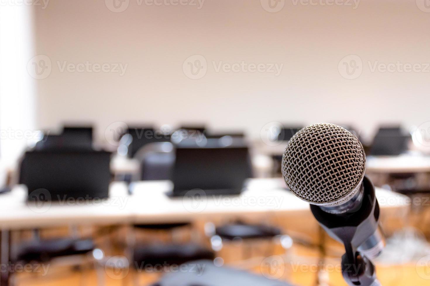 cierre el micrófono para el altavoz con espacio de copia y una computadora portátil en el fondo de la mesa en la sala de seminarios foto