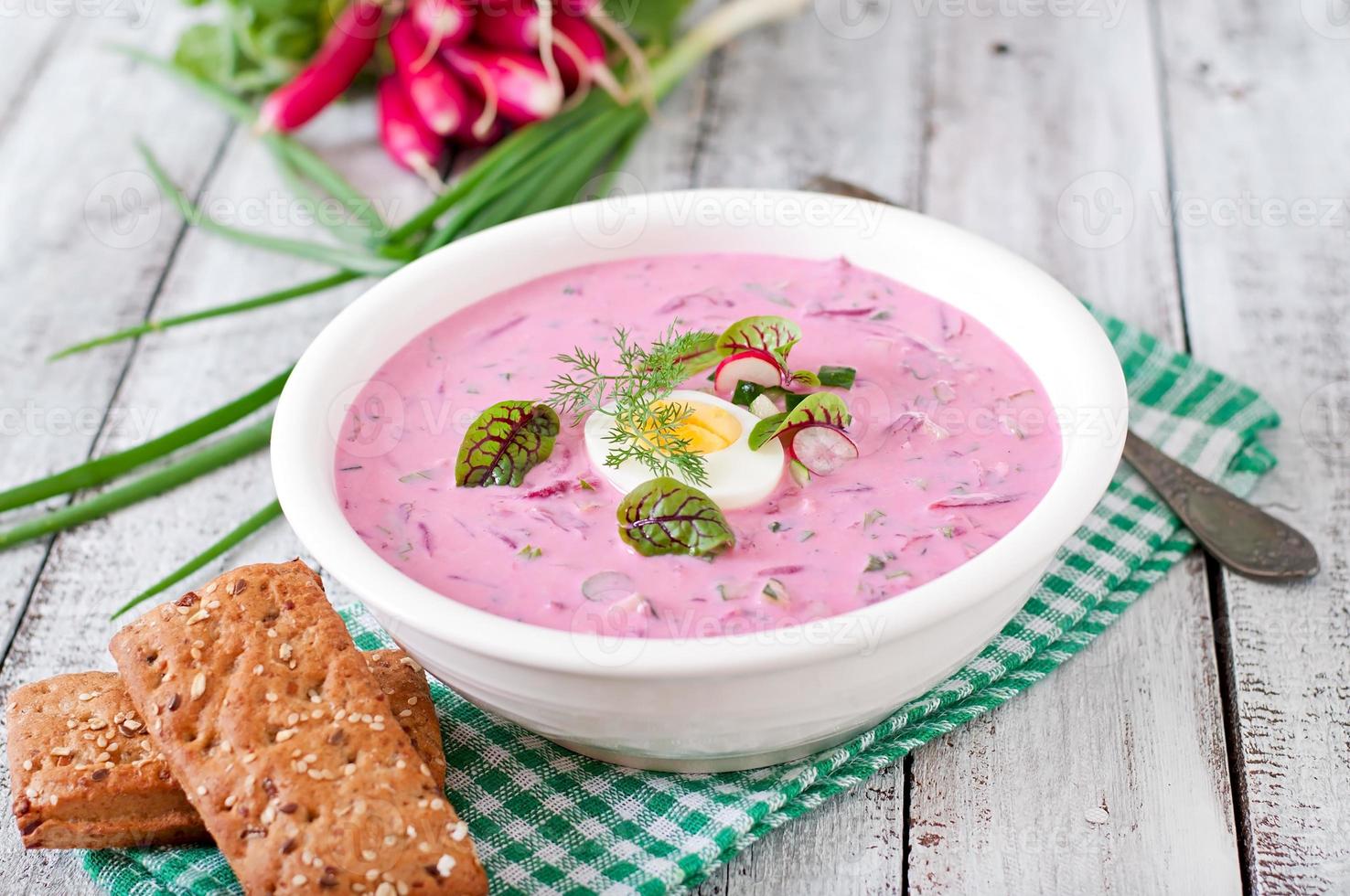 Cold beet soup on yogurt with egg, radishes and cucumbers photo