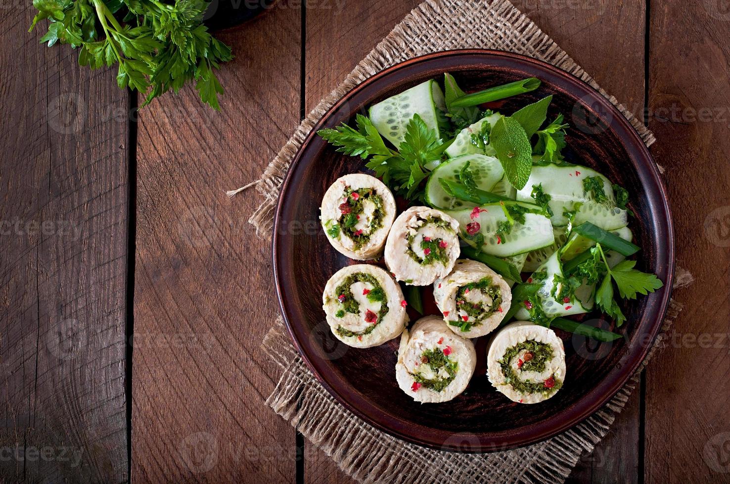 Steamed chicken rolls with greens and fresh vegetable salad on a brown plate photo