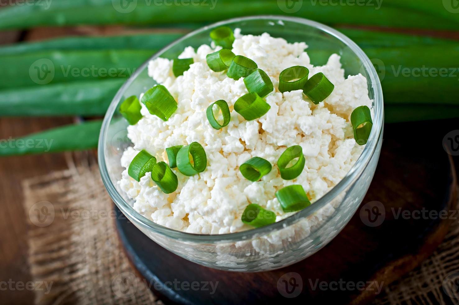 Useful cottage cheese with chives in a glass bowl on a wooden background. photo