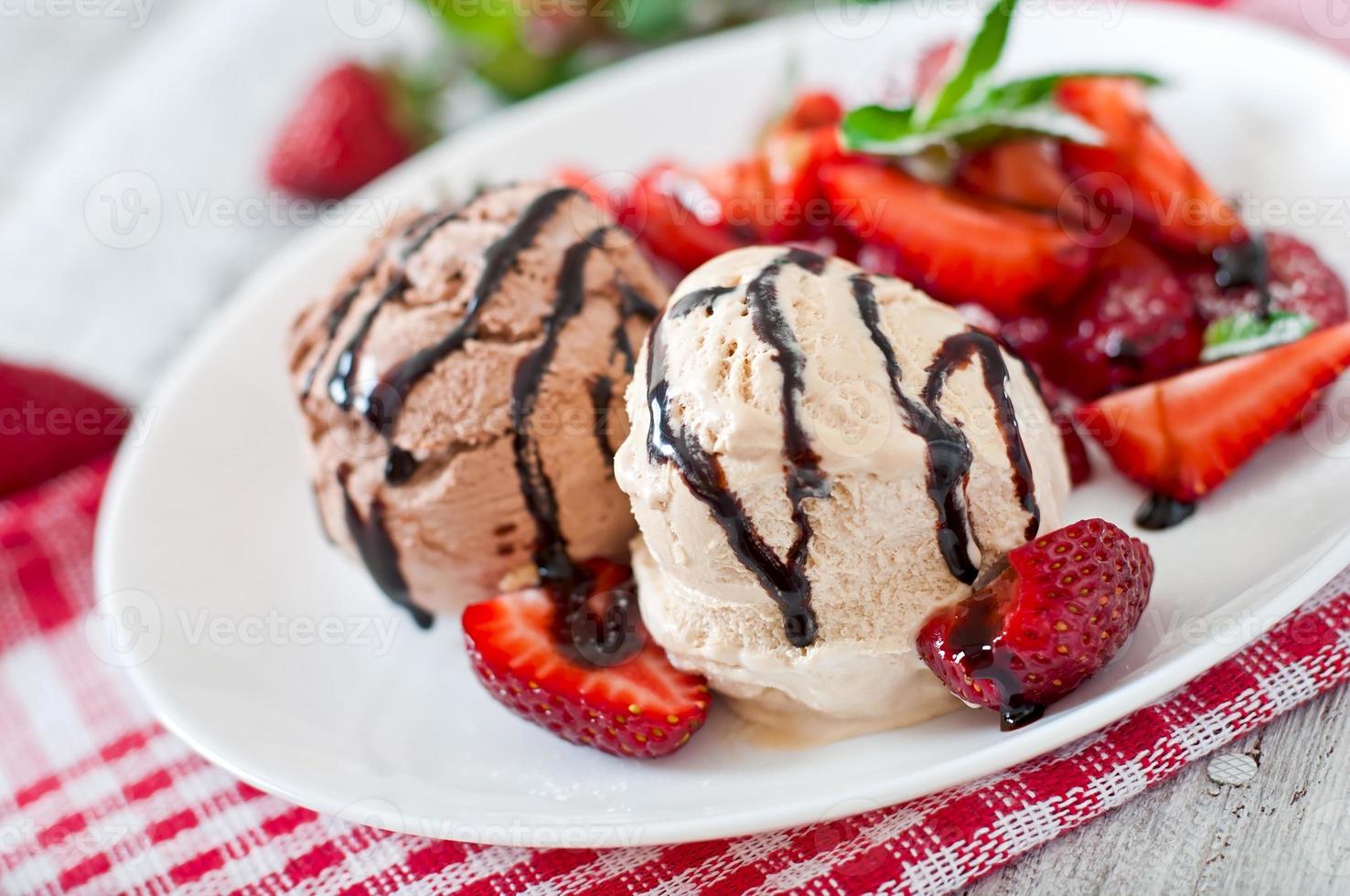 Ice cream with strawberries and chocolate on a white plate photo