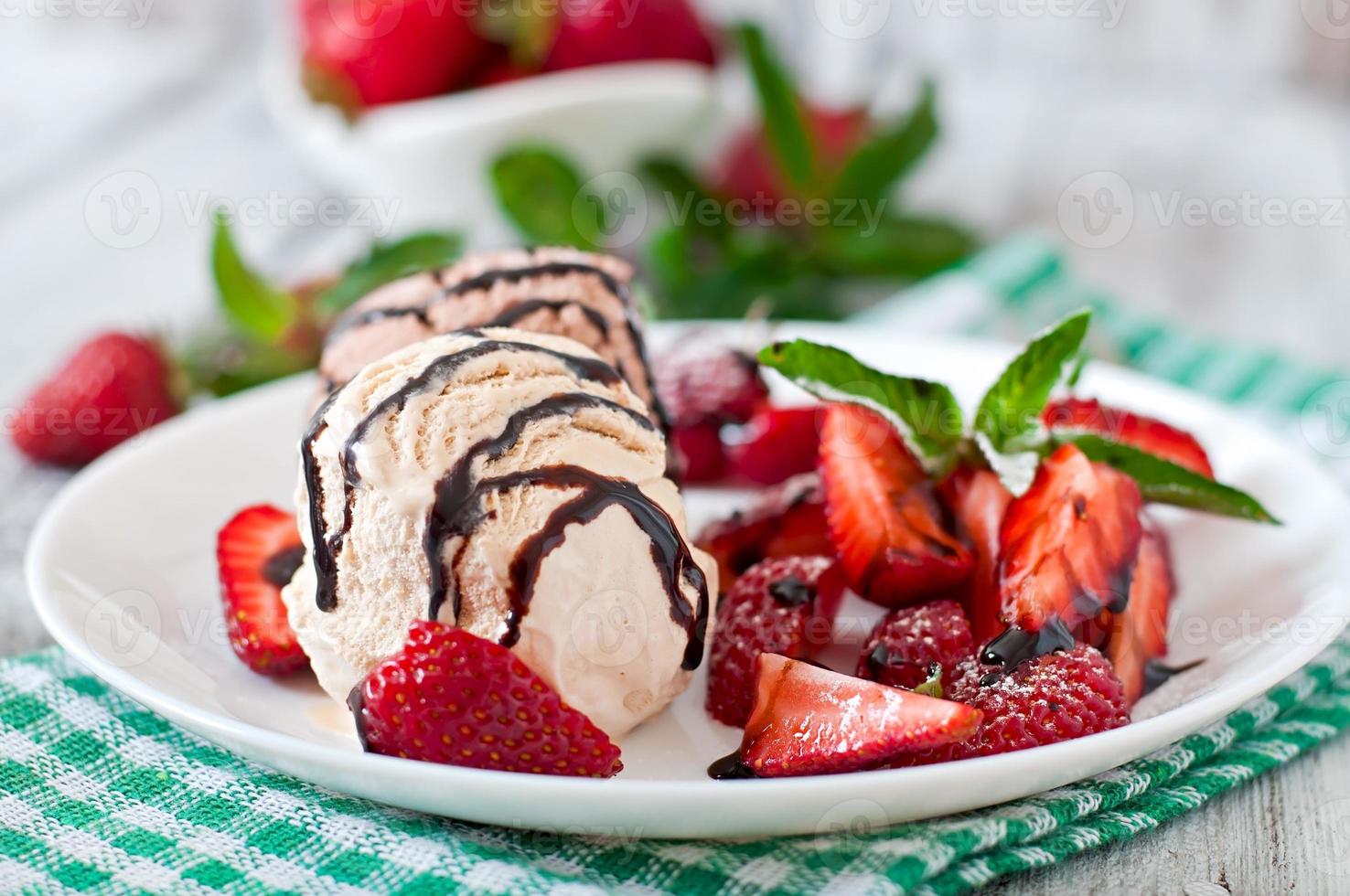 Ice cream with strawberries and chocolate on a white plate photo