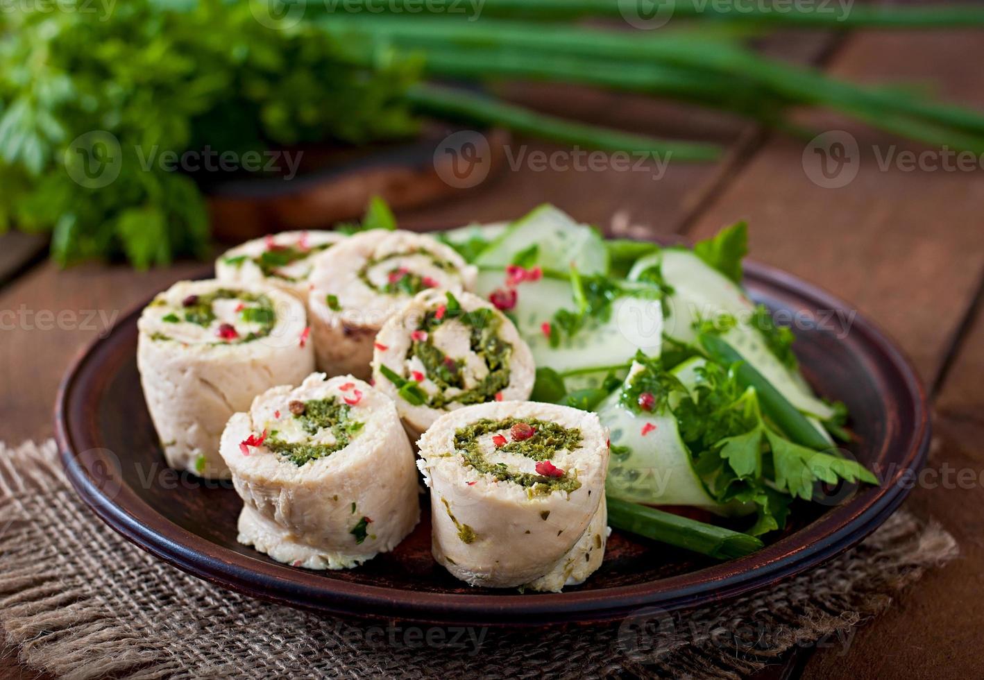 Steamed chicken rolls with greens and fresh vegetable salad on a brown plate photo