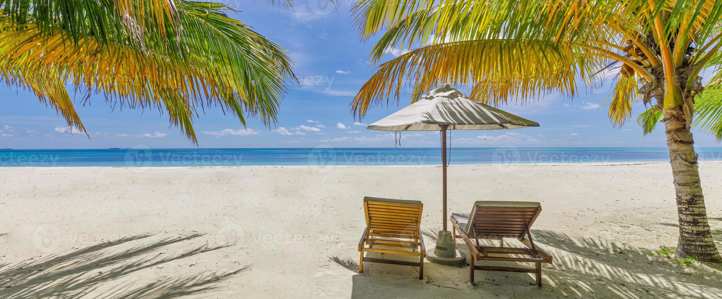 increíble playa de vacaciones. un par de sillas juntas junto a la pancarta del mar. concepto de luna de miel de vacaciones románticas de verano. paisaje de isla tropical. panorama costero tranquilo, horizonte costero de arena relajante, hojas de palma foto