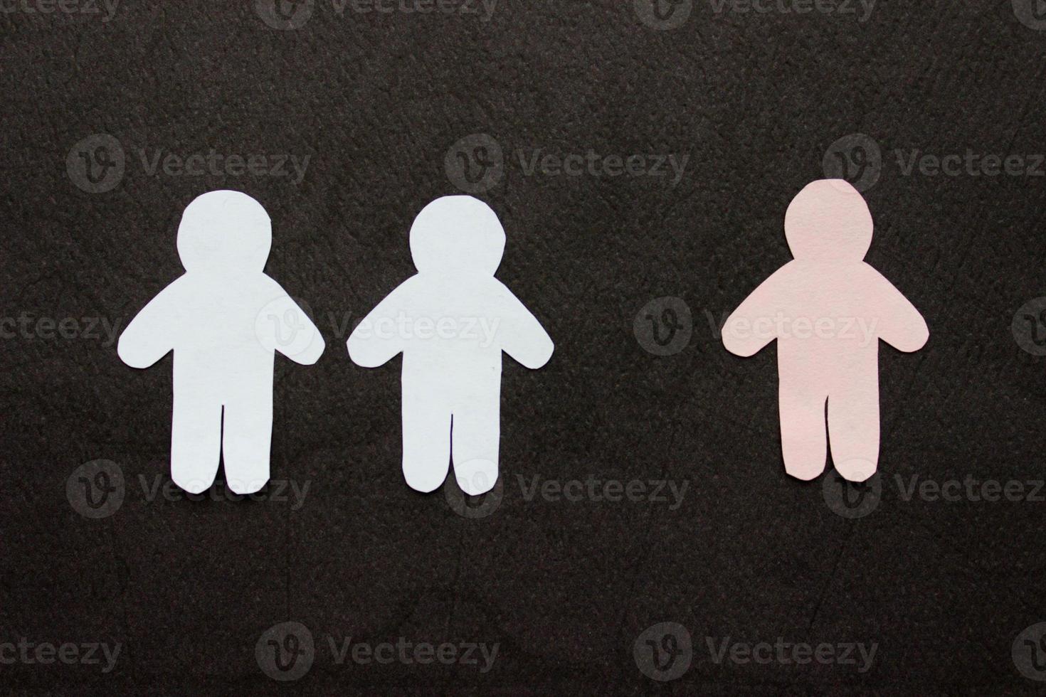 Silhouettes of people cut from white and pink paper on a black background. Two people stands in front of one person pink figure. Communication, leadership, teamwork concept photo