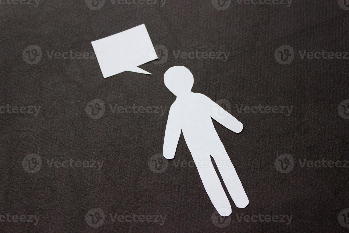 Silhouette of man cut out of white paper. With speech-bubble. In the center of the photo on a black background