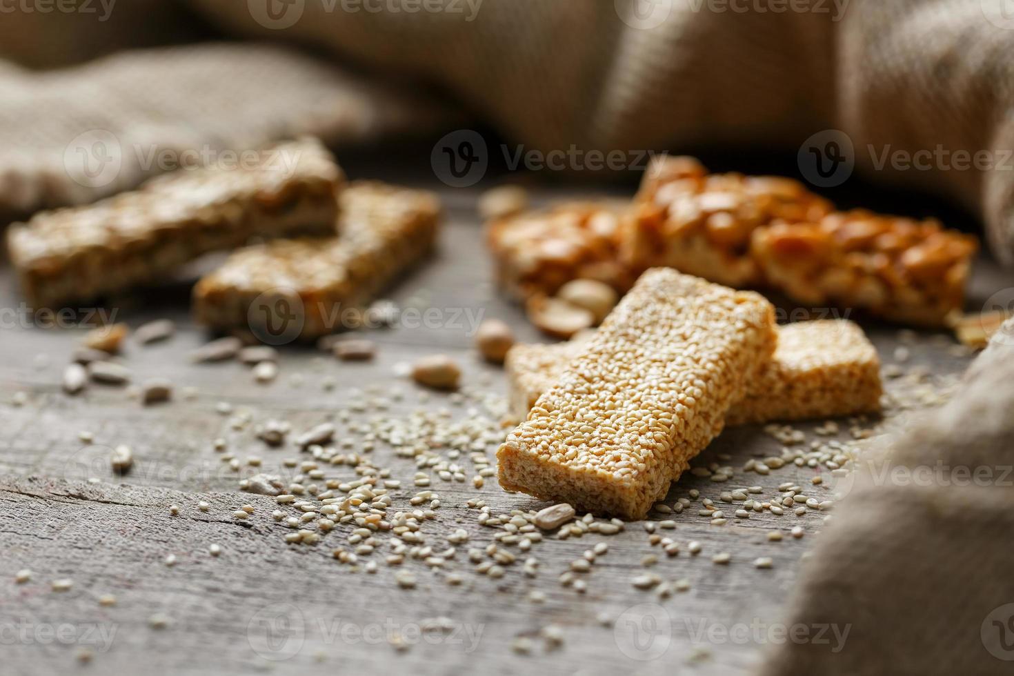 Assorted kozinaki, on old vintage background, with burlap fabric. Country style. Delicious sweets from the seeds of sunflower, sesame and peanuts, covered with shiny glaze. photo