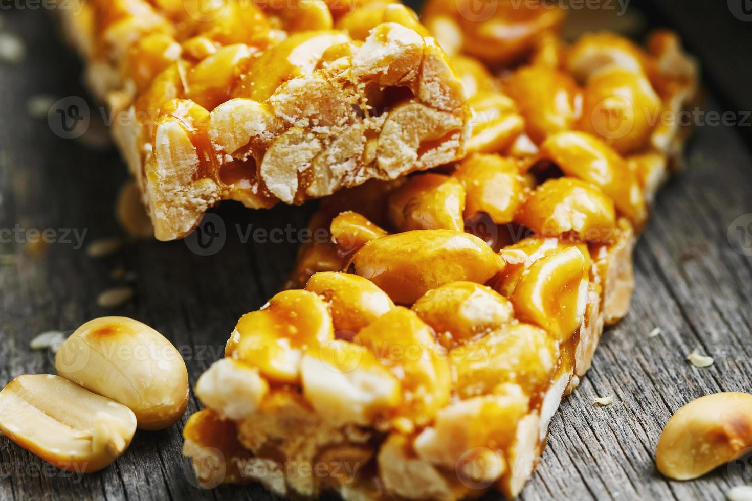 barra de dulces de maní sobre un fondo vintage con arpillera. deliciosos dulces orientales gozinaki de semillas de girasol, sésamo y cacahuetes, cubiertos de miel con un glaseado brillante foto