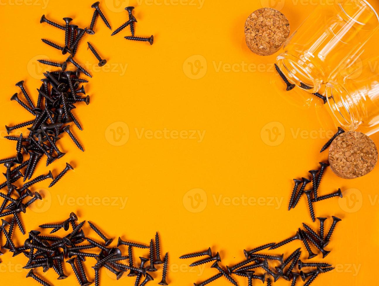 Many metal self-tapping screws made of steel in a glass, in bucket jar. self-tapping screw for metal, for iron, chrome-plated self-tapping screw, on an orange yellow background, photo