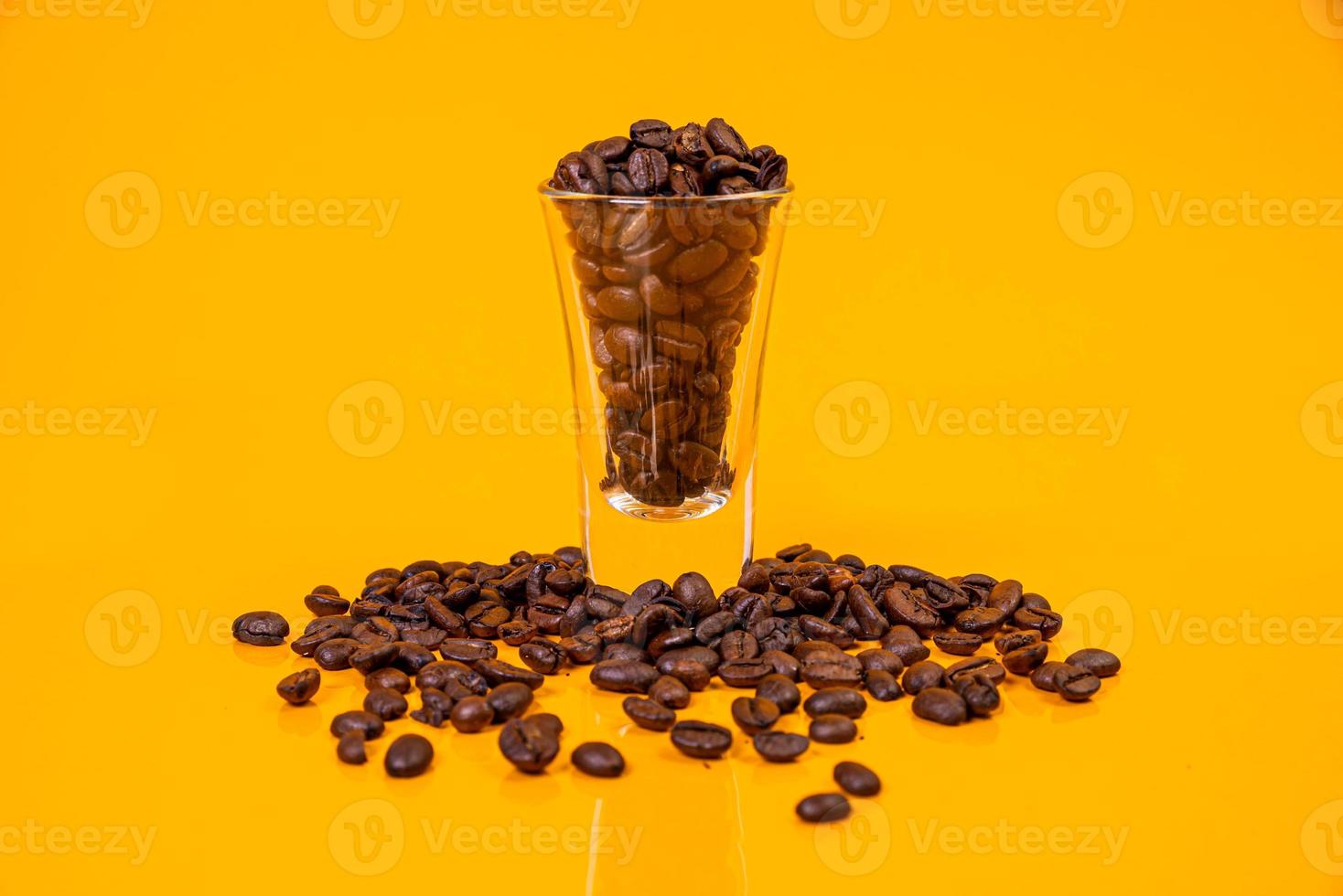 Dropped Many roasted coffee beans in a glass, in bucket jar. self-tapping screw for metal, for iron, chrome-plated self-tapping screw, orange yellow background photo