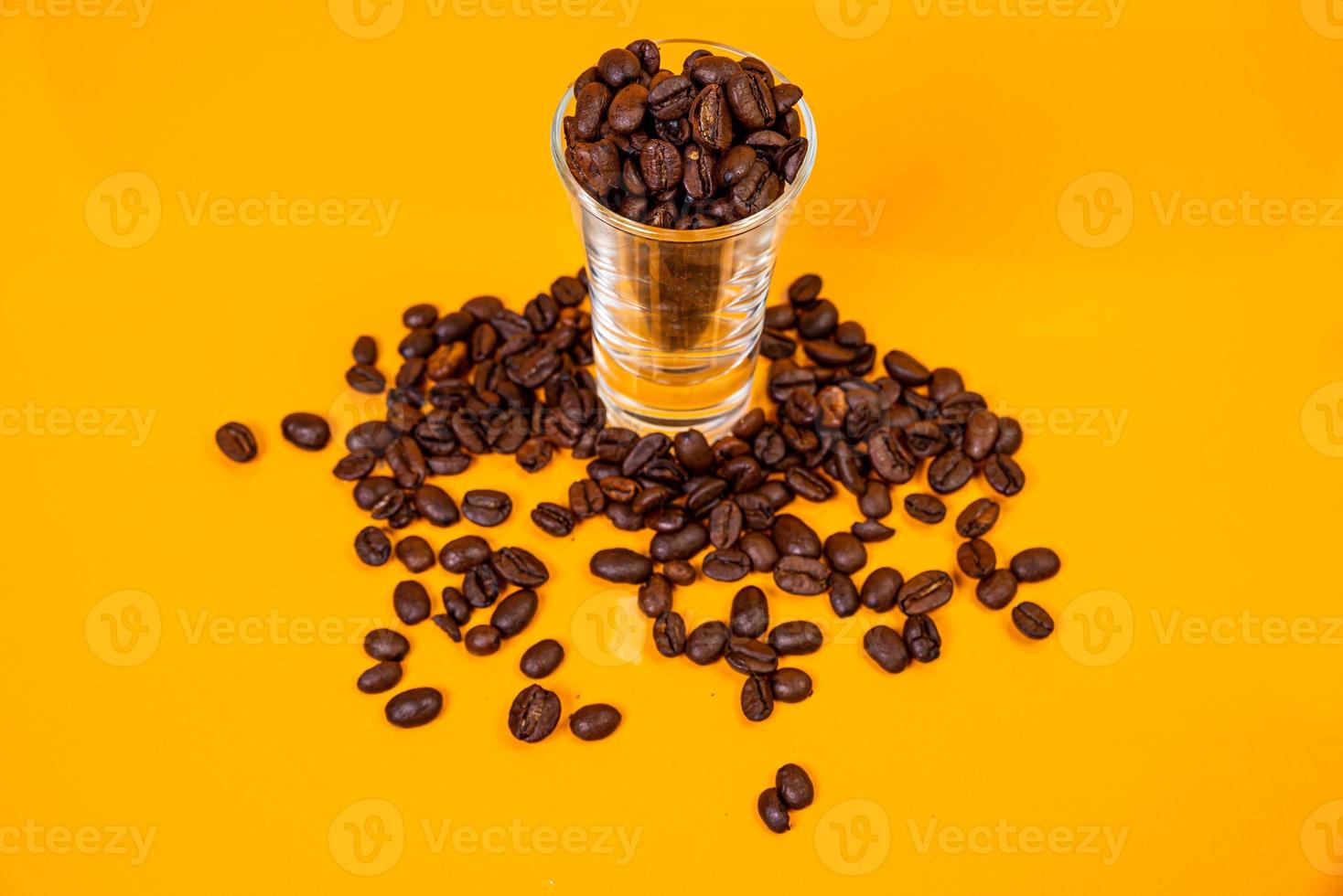 Dropped Many roasted coffee beans in a glass, in bucket jar. self-tapping screw for metal, for iron, chrome-plated self-tapping screw, orange yellow background photo