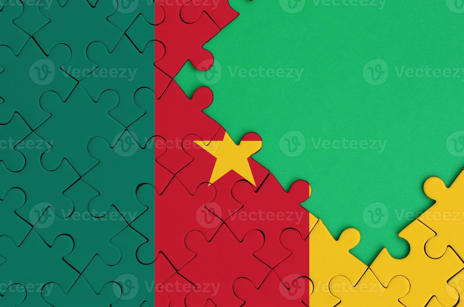 Cameroon flag is depicted on a completed jigsaw puzzle with free green copy space on the right side photo