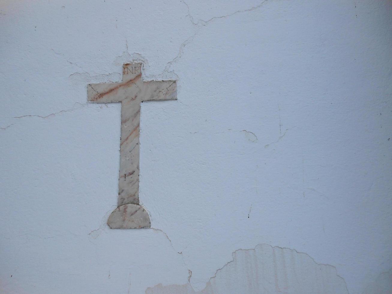 Marble cross on white wall background photo