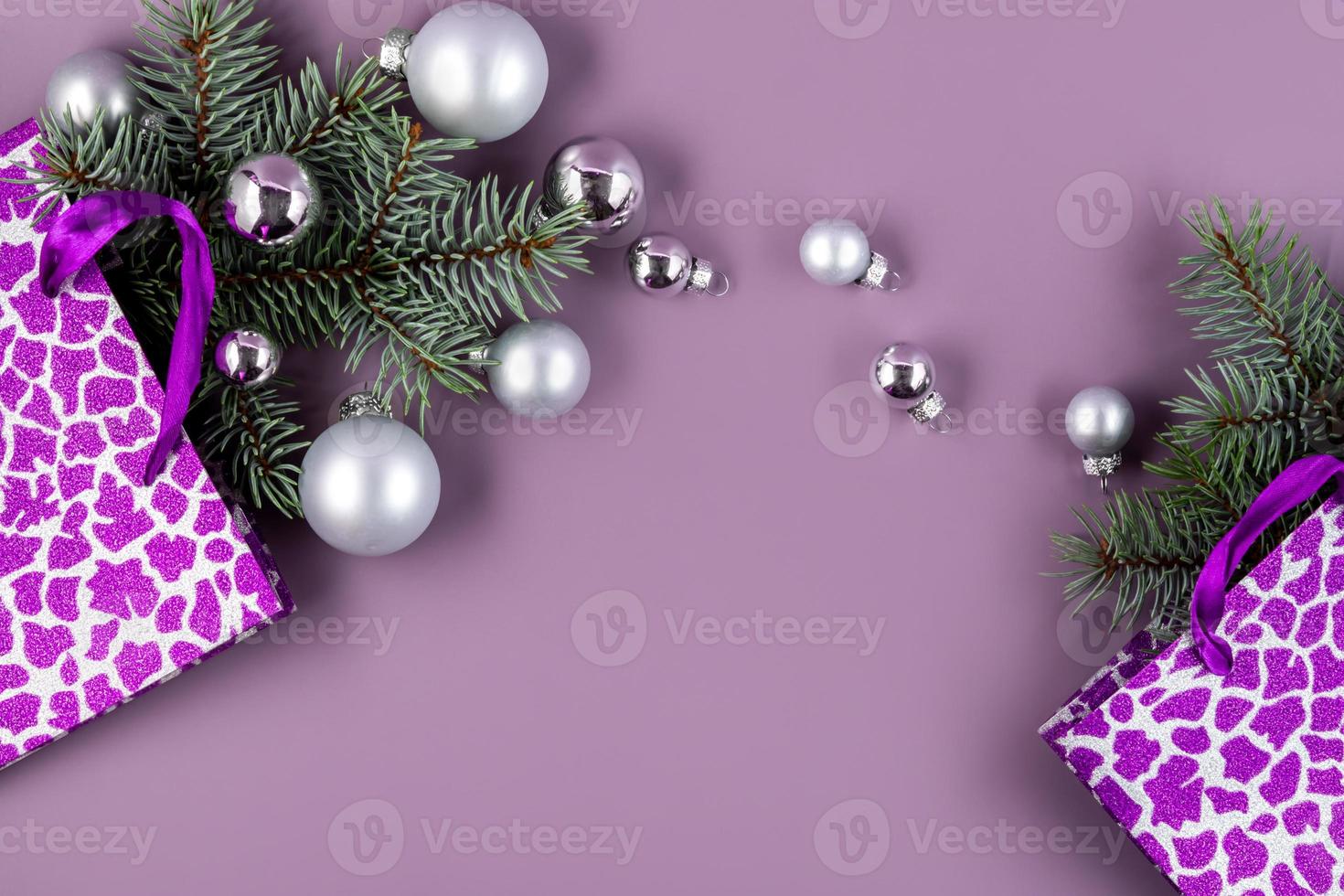 The concept of a Christmas background. Top view of silver balls from a Christmas gift box with fir branches on a fashionable purple background. photo