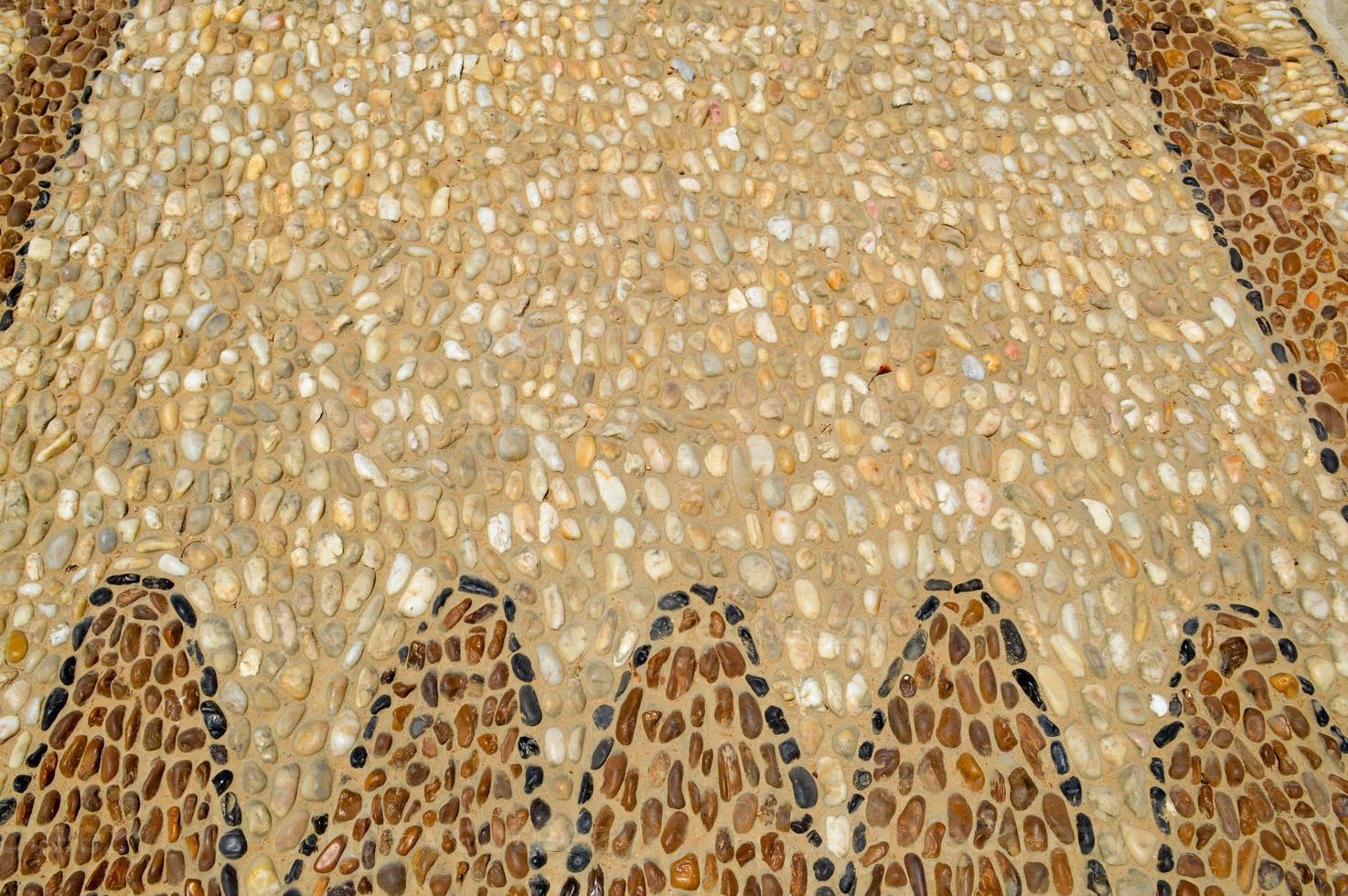 The texture of the stone wall, the road from small round and oval stones with abstract lines laid out patterns of sandy seams of natural old yellow black brown. The background photo