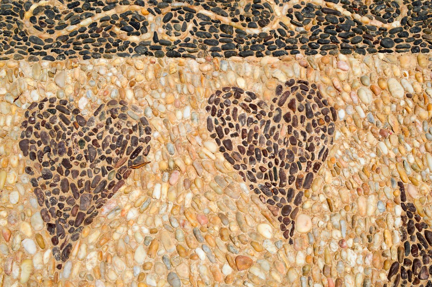 The texture of the stone wall, the road from small round and oval stones with abstracted lines of patterns of two hearts sandy seams of natural old yellow black brown. The background photo