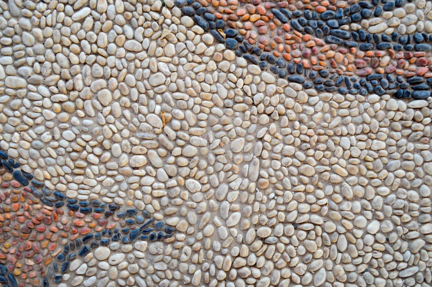 The texture of the stone wall, the road from small round and oval stones with abstract lines laid out patterns of sandy seams of natural old yellow black brown. The background photo