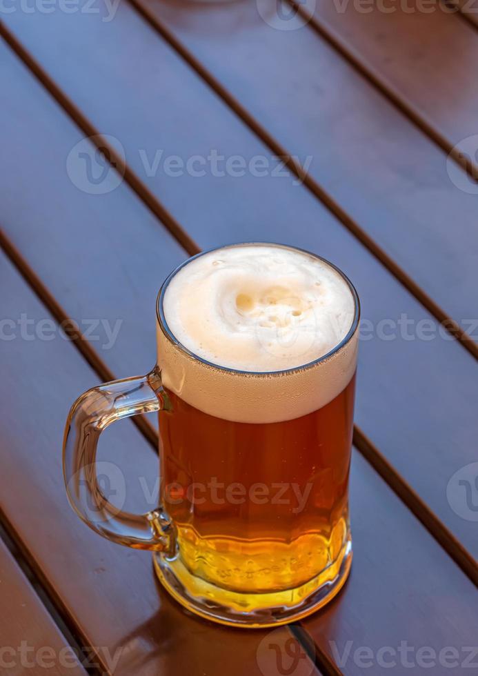 Mug of beer with white dense foam on a wooden background. photo