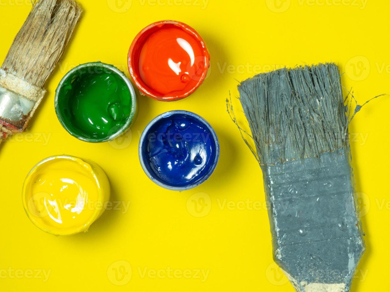 Jars of paint and old brushes on a yellow background. Banks of gouache. Bright background.    Artist's workshop. photo