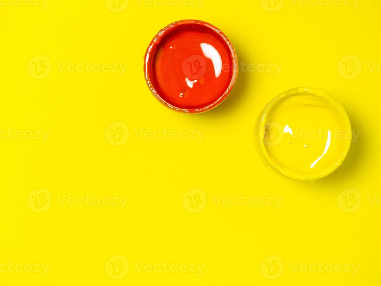 Jars with yellow and red paint on a yellow background. jar of gouache. Bright background. Creative background. photo