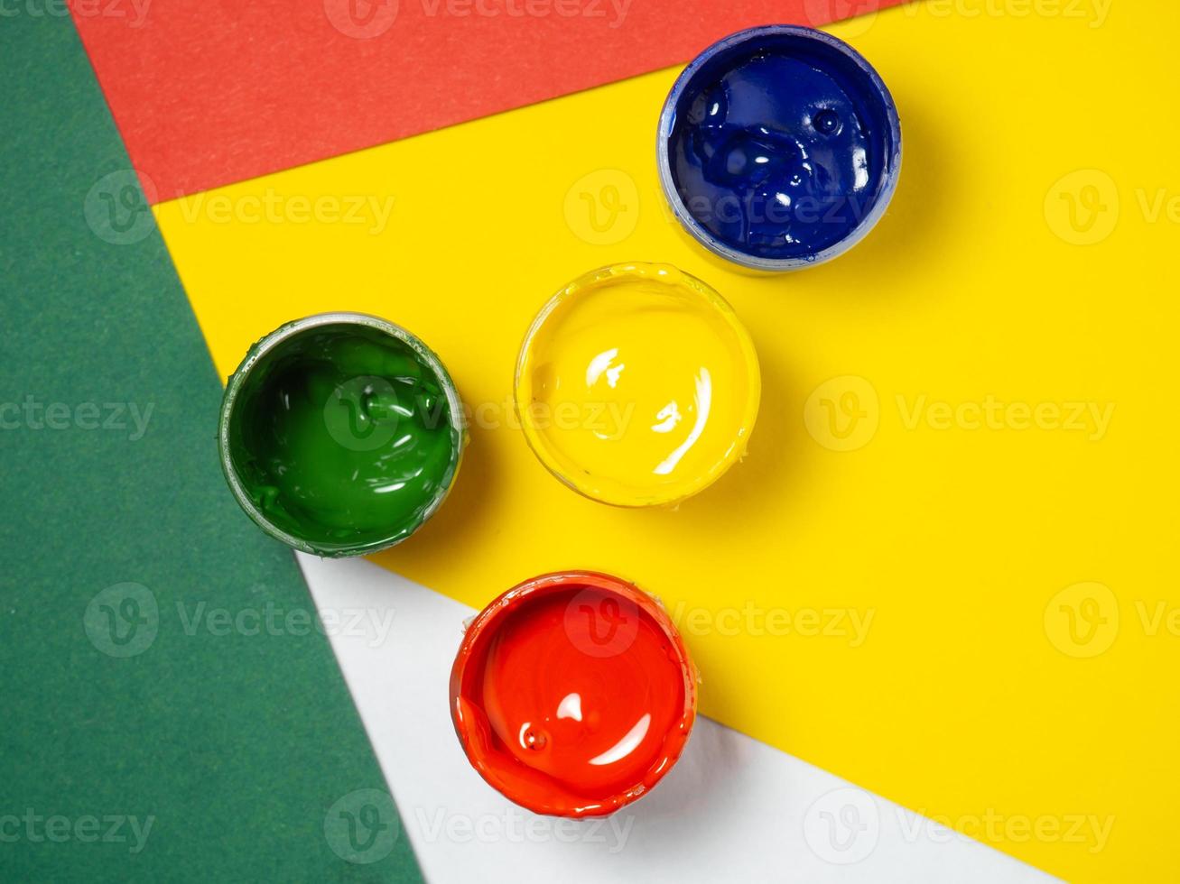 Jars with yellow, green and red paint on a color pepper. Banks of gouache.  Traffic lights. Creative background. Artist's workshop. photo