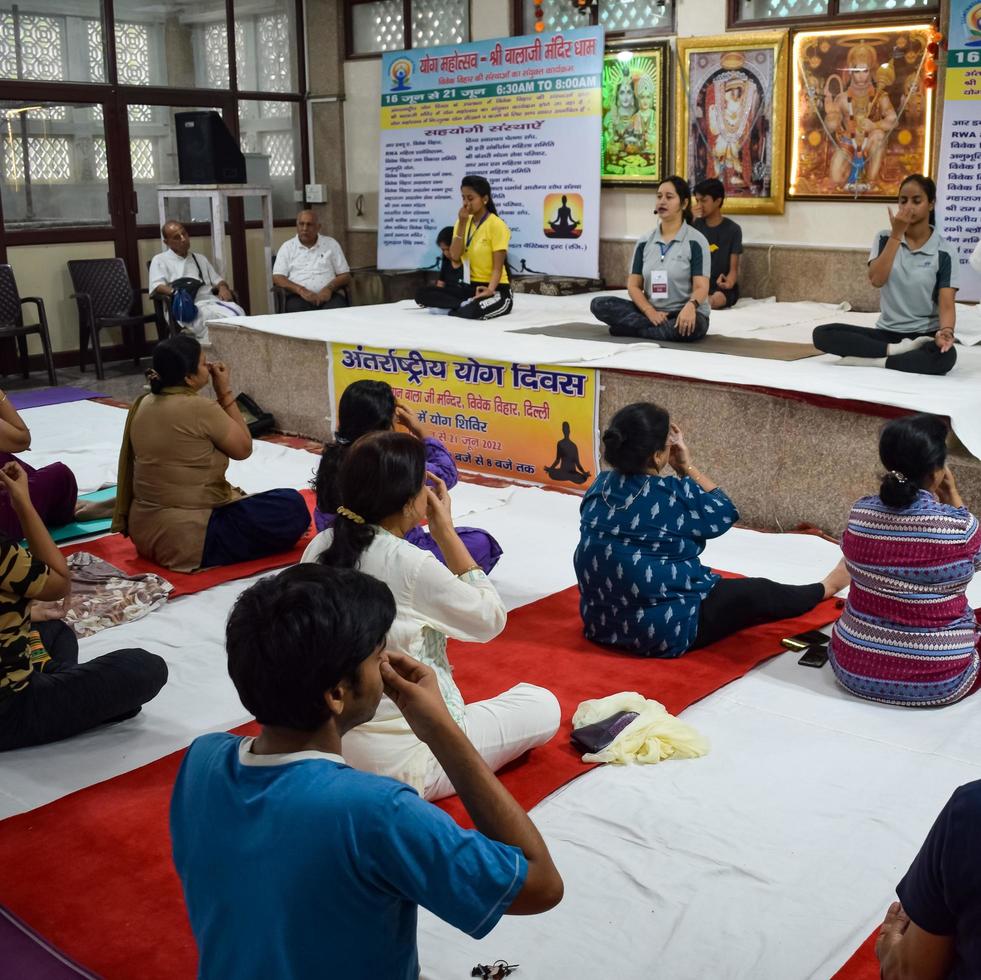 New Delhi, India, June 19 2022 -Group Yoga exercise session for people of different age groups in Balaji Temple, Vivek Vihar, International Yoga Day, Big group of adults attending yoga class in temple photo