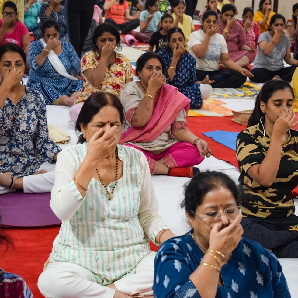 New Delhi, India, June 19 2022 -Group Yoga exercise session for people of different age groups in Balaji Temple, Vivek Vihar, International Yoga Day, Big group of adults attending yoga class in temple photo