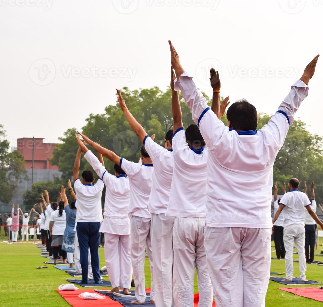 Group Yoga exercise session for people of different age groups at cricket stadium in Delhi on International Yoga Day, Big group of adults attending yoga session photo