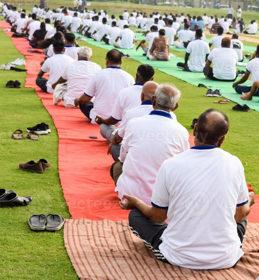 Group Yoga exercise session for people of different age groups at cricket stadium in Delhi on International Yoga Day, Big group of adults attending yoga session photo