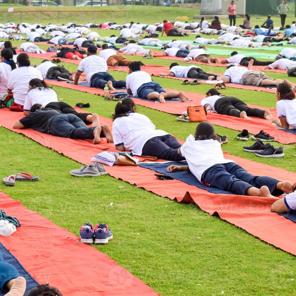 Group Yoga exercise session for people of different age groups at cricket stadium in Delhi on International Yoga Day, Big group of adults attending yoga session photo