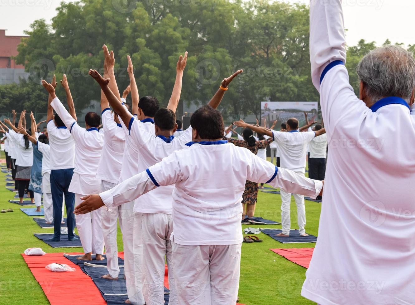 Group Yoga exercise session for people of different age groups at cricket stadium in Delhi on International Yoga Day, Big group of adults attending yoga session photo