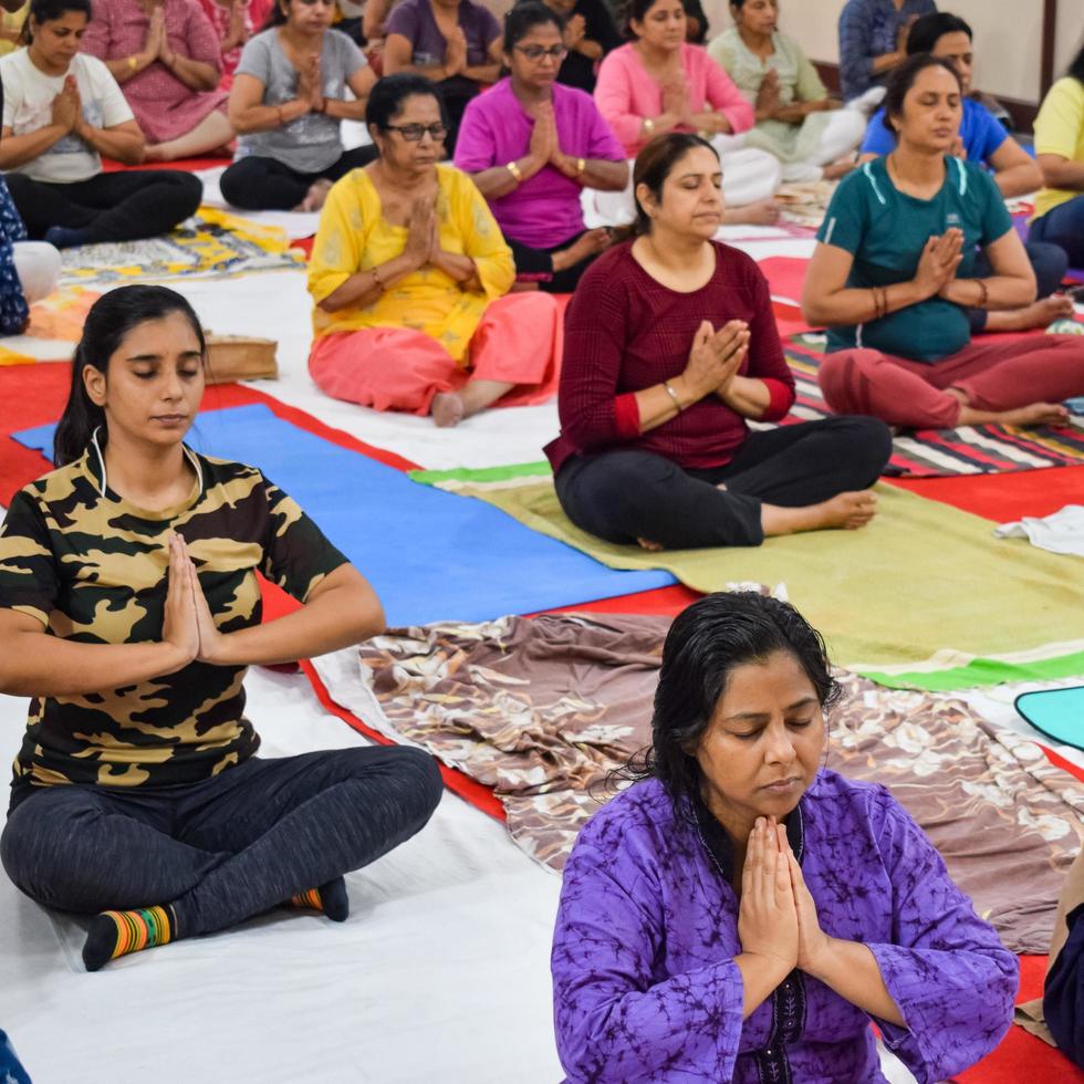 New Delhi, India, June 19 2022 -Group Yoga exercise session for people of different age groups in Balaji Temple, Vivek Vihar, International Yoga Day, Big group of adults attending yoga class in temple photo