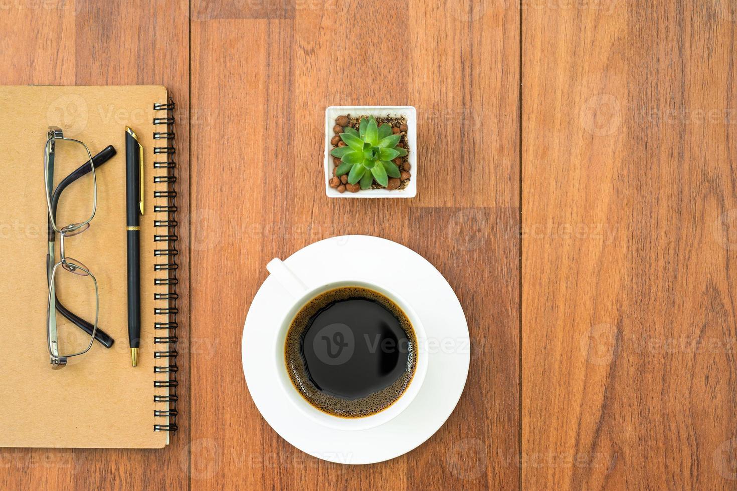 Eyeglasse and notepad with coffee cup on wood deck photo