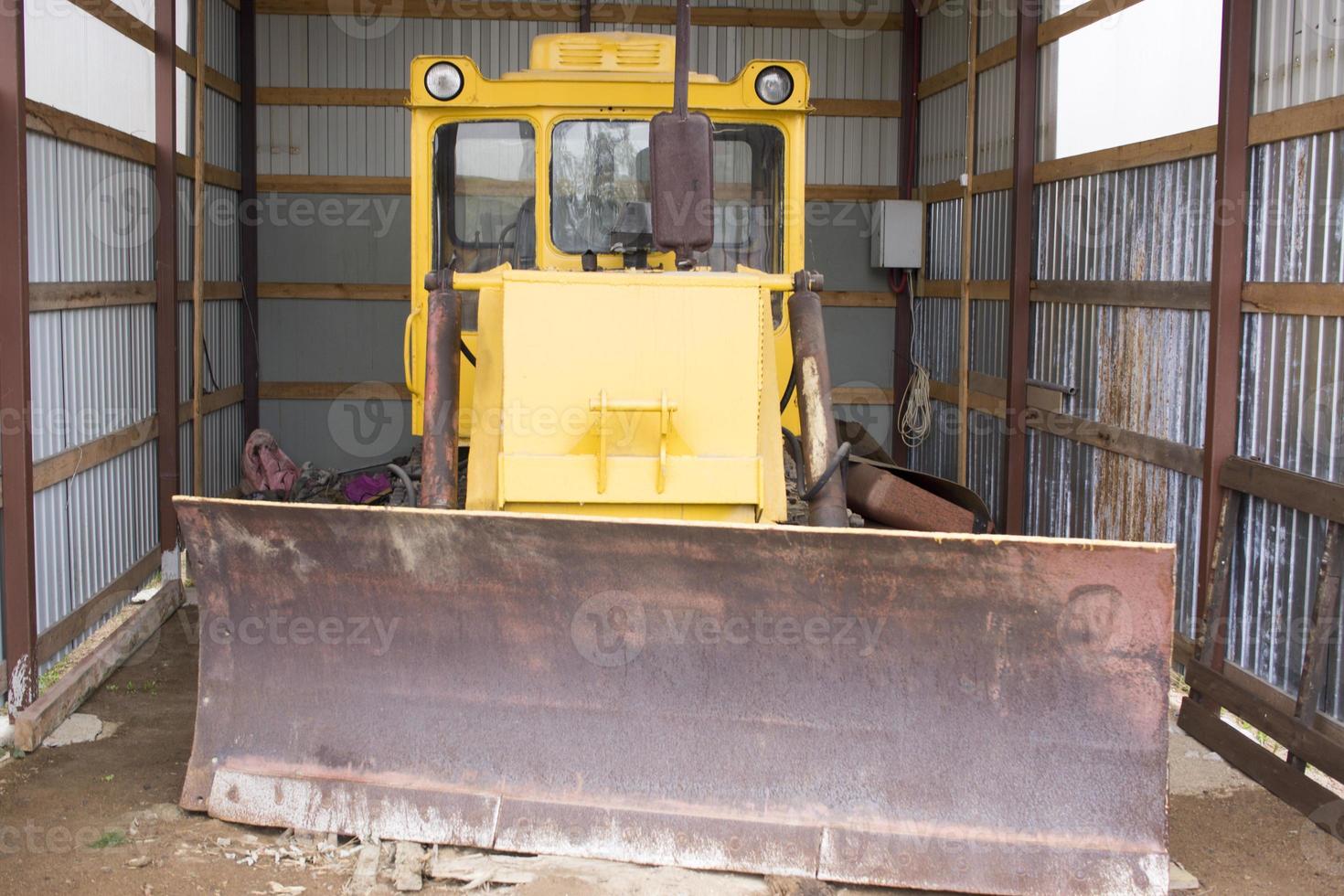 Large wheeled tractor with a dozer blade for clearing roads from snow. Yellow wheel loader in the garage. photo