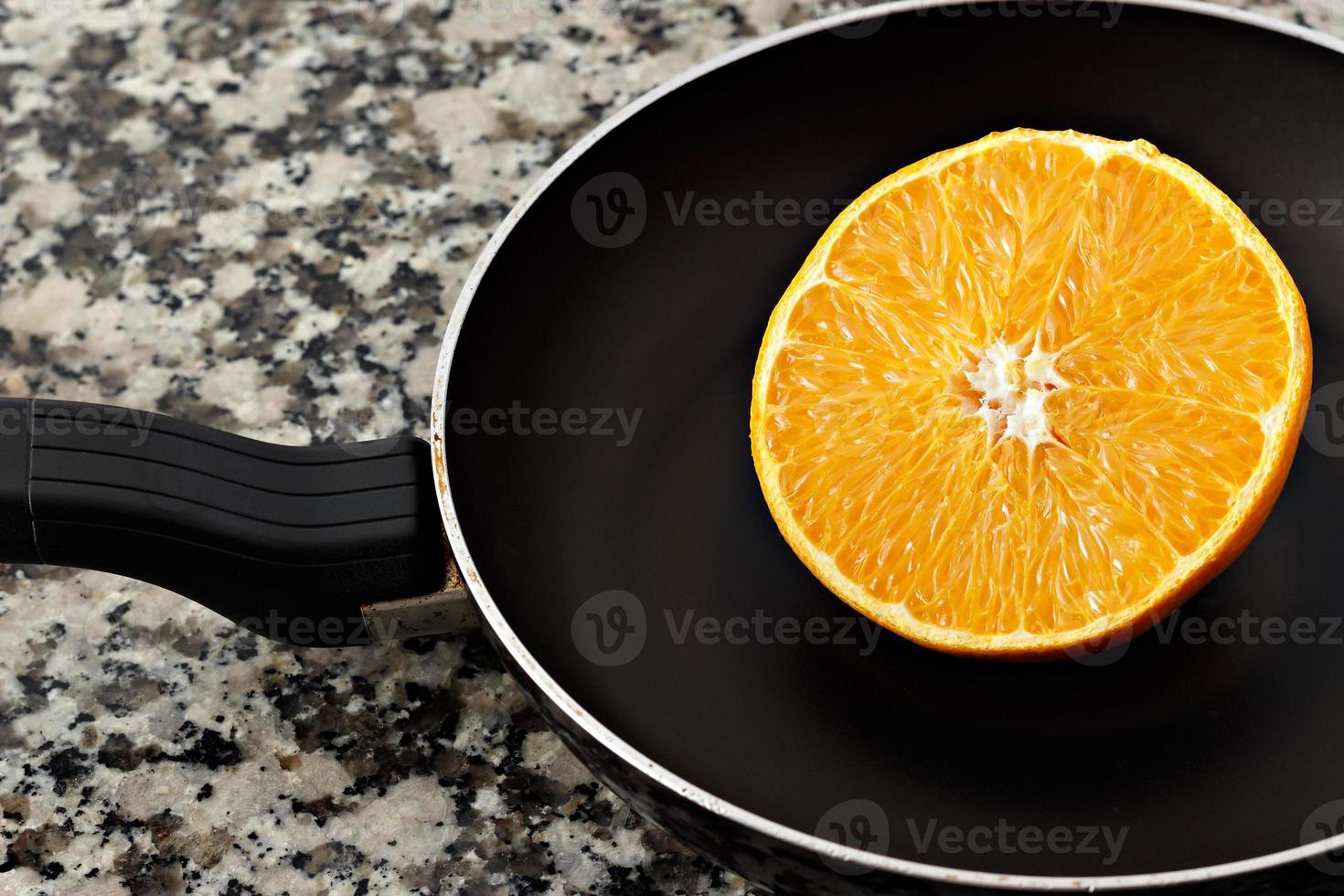 Juicy half orange in a frying pan on the kitchen counter. Horizontal image. photo