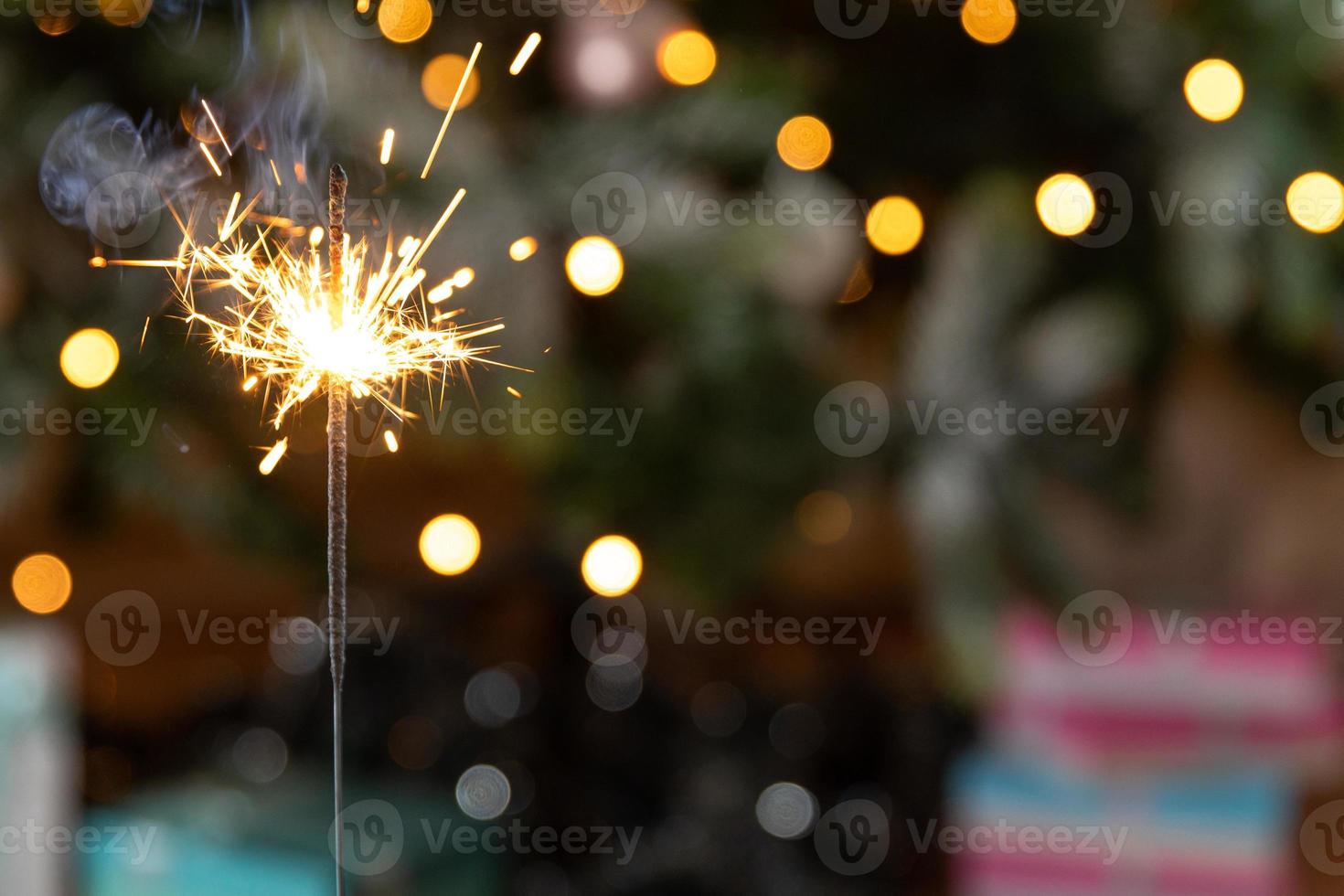 Christmas glittering sparklers candle burns in Christmas tree background. Xmas lighting decoration at home indoor. Festive Magic sparks lights for holiday party. Christmas eve with fireworks. photo