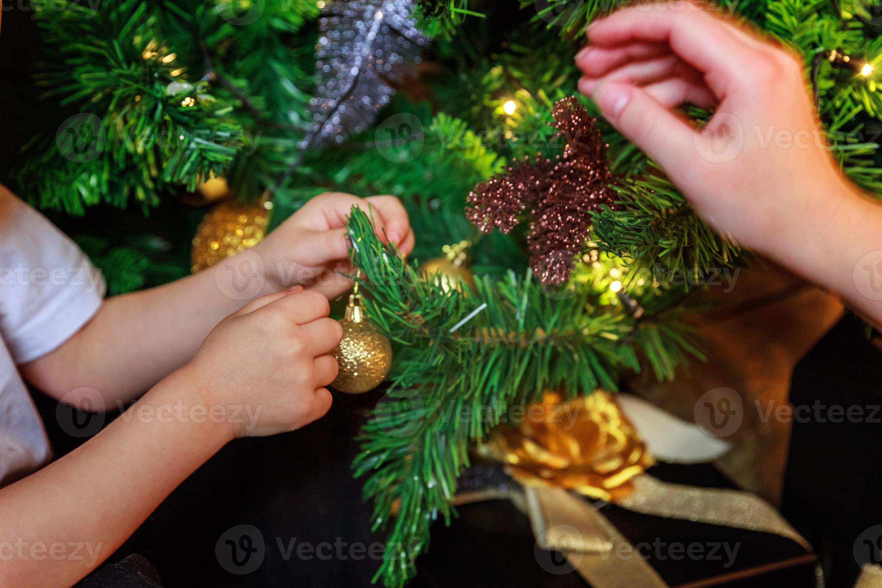 Close up baby hands decorating Christmas tree on Christmas eve at home.  Young kid with winter decoration. Happy family at home. Christmas New Year  december time for celebration concept. 14070308 Stock Photo at Vecteezy