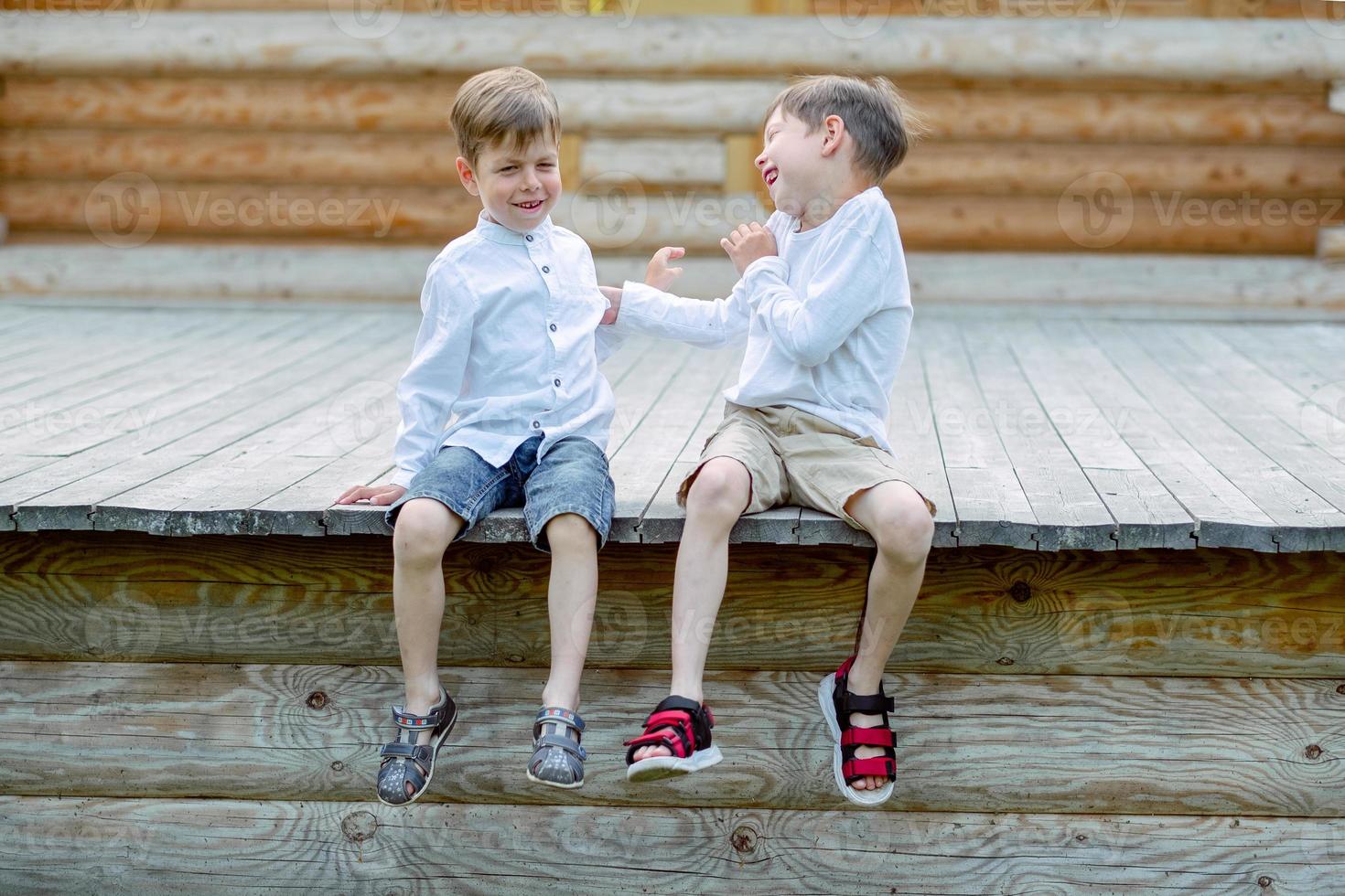 los niños están sentados en el banco. 2 hermanos están jugando. los amigos están jugando. los niños se ríen foto