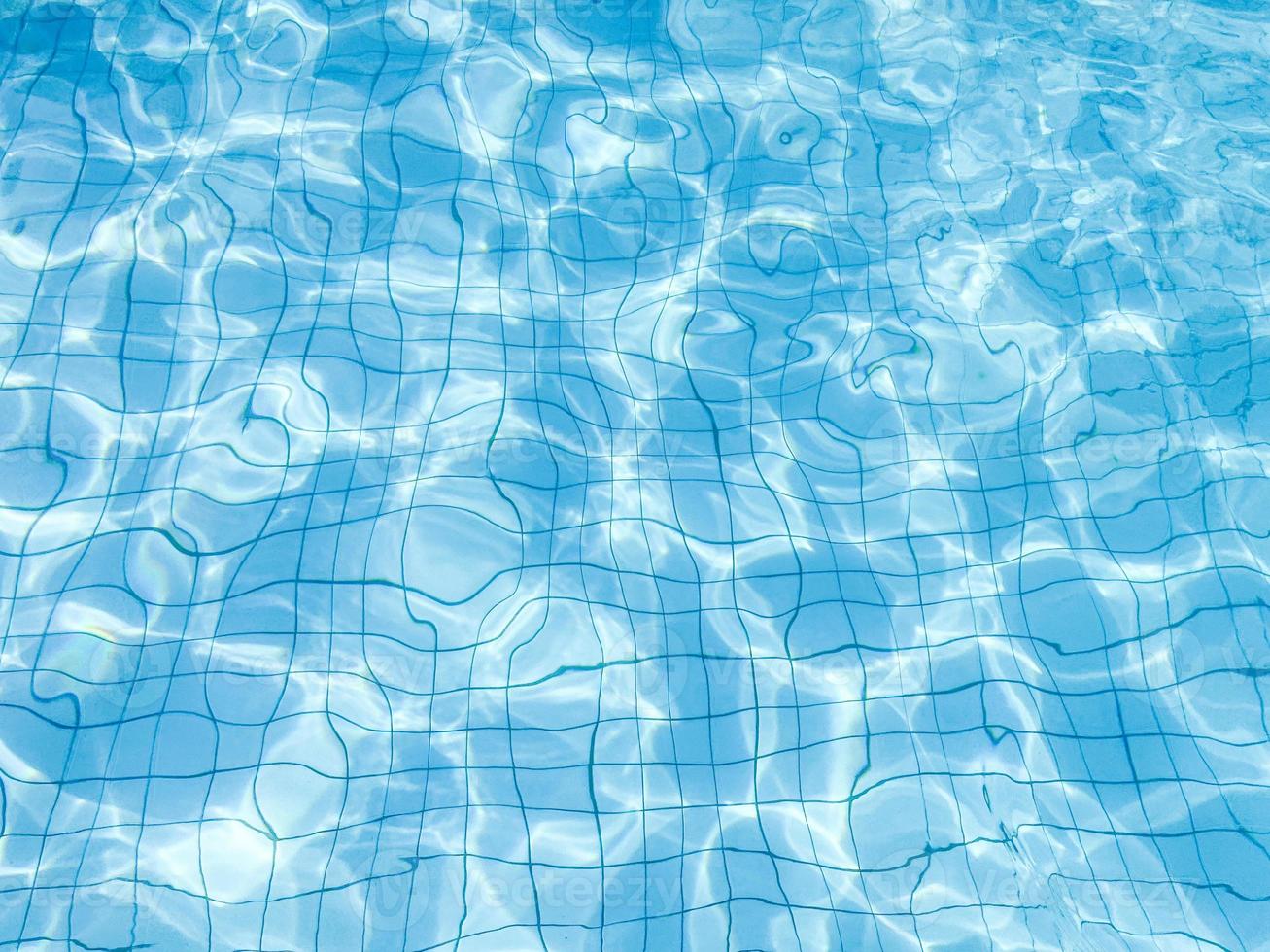 blue water wave pattern in swimming pool as the sun shines down during the day. Soft and selective focus. photo
