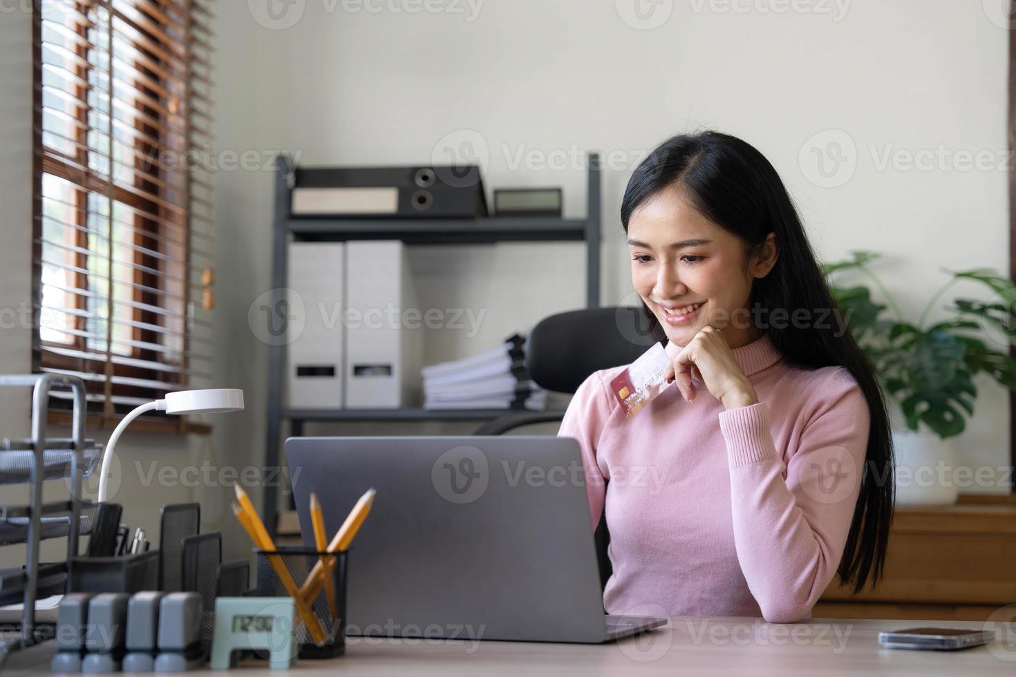 Happy asian Business woman pay online using mobile phone at the office. photo