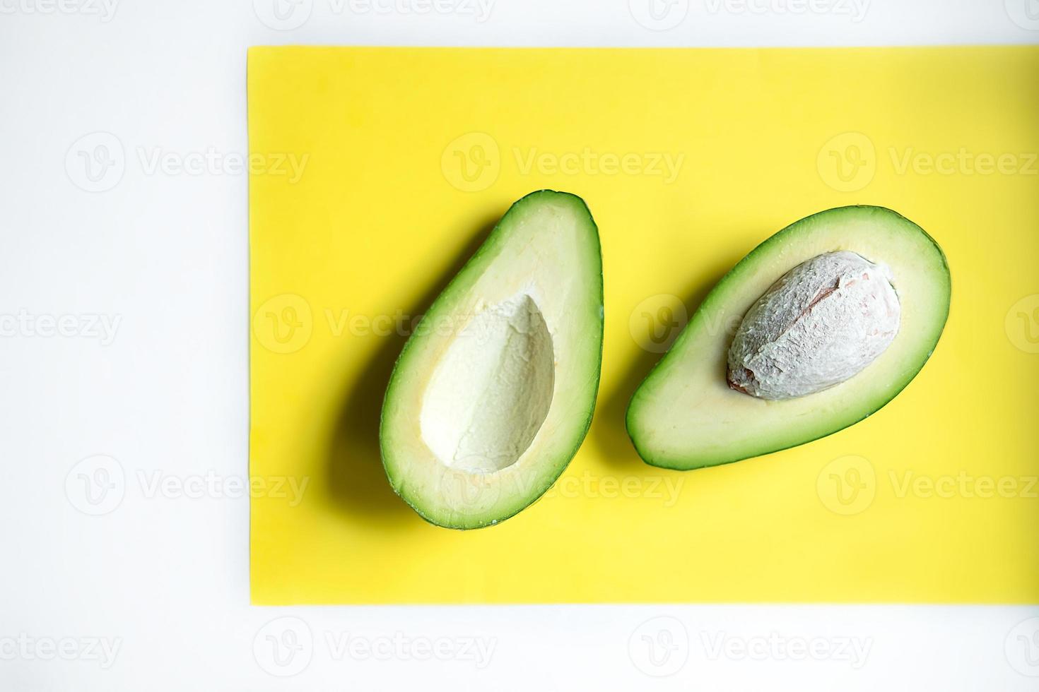 Avocado cut in half. Avocado on a yellow background. photo