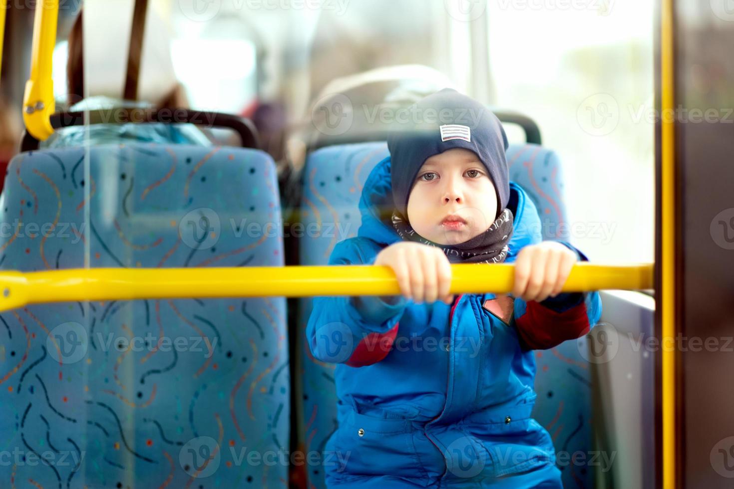 little boy rides a bus. A serious boy looks at the camera photo