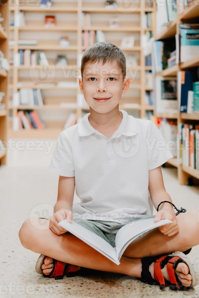 niño en la biblioteca de la escuela. los niños leen libros. niño leyendo y estudiando. niños en la librería. niño de preescolar inteligente inteligente que elige libros para pedir prestados. foto