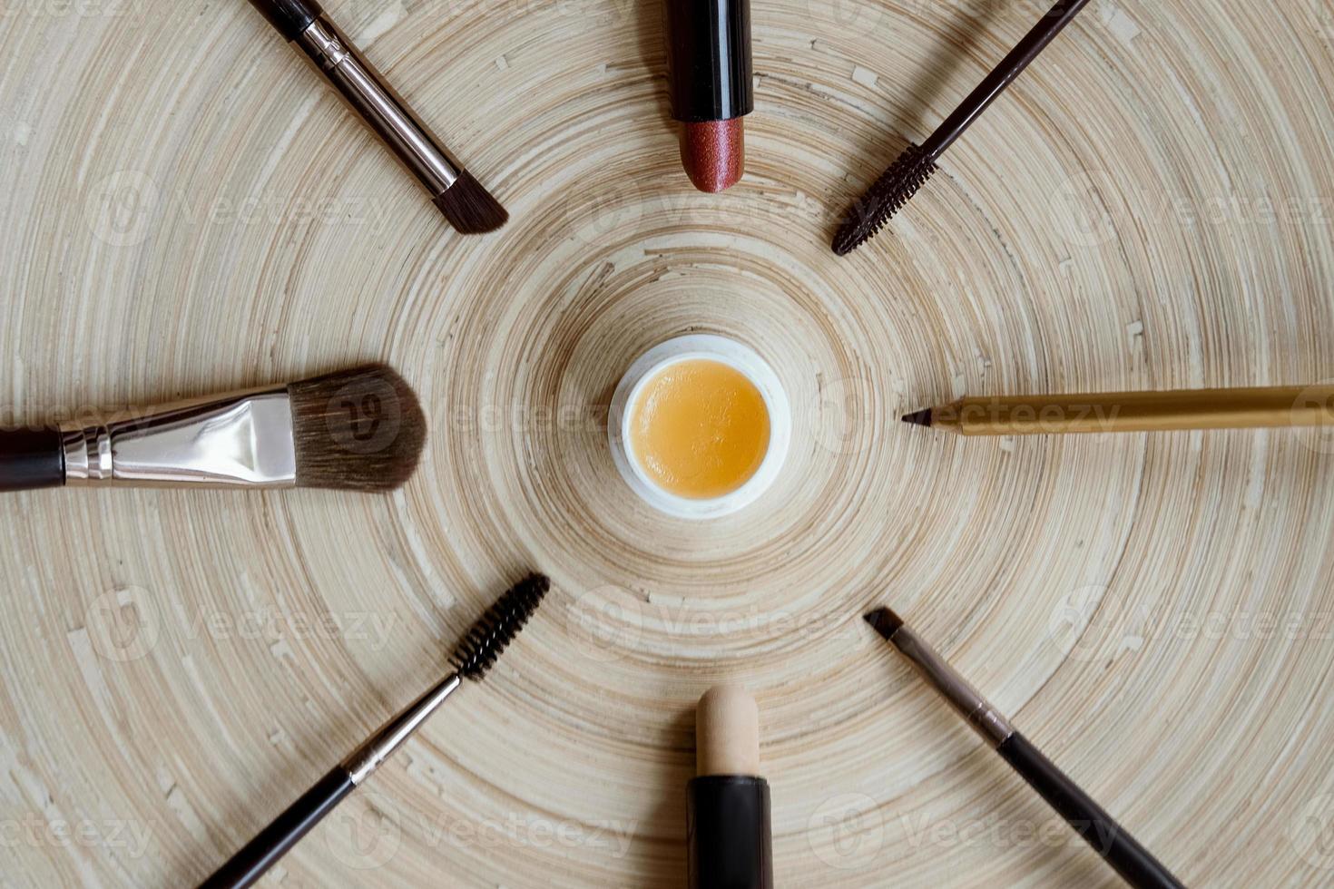 Natural vegan makeup on a wooden background - mascara, brushes, lipstick, gloss, pencil. Flat lay of cosmetics on a wooden background. unusual watches from cosmetics. photo