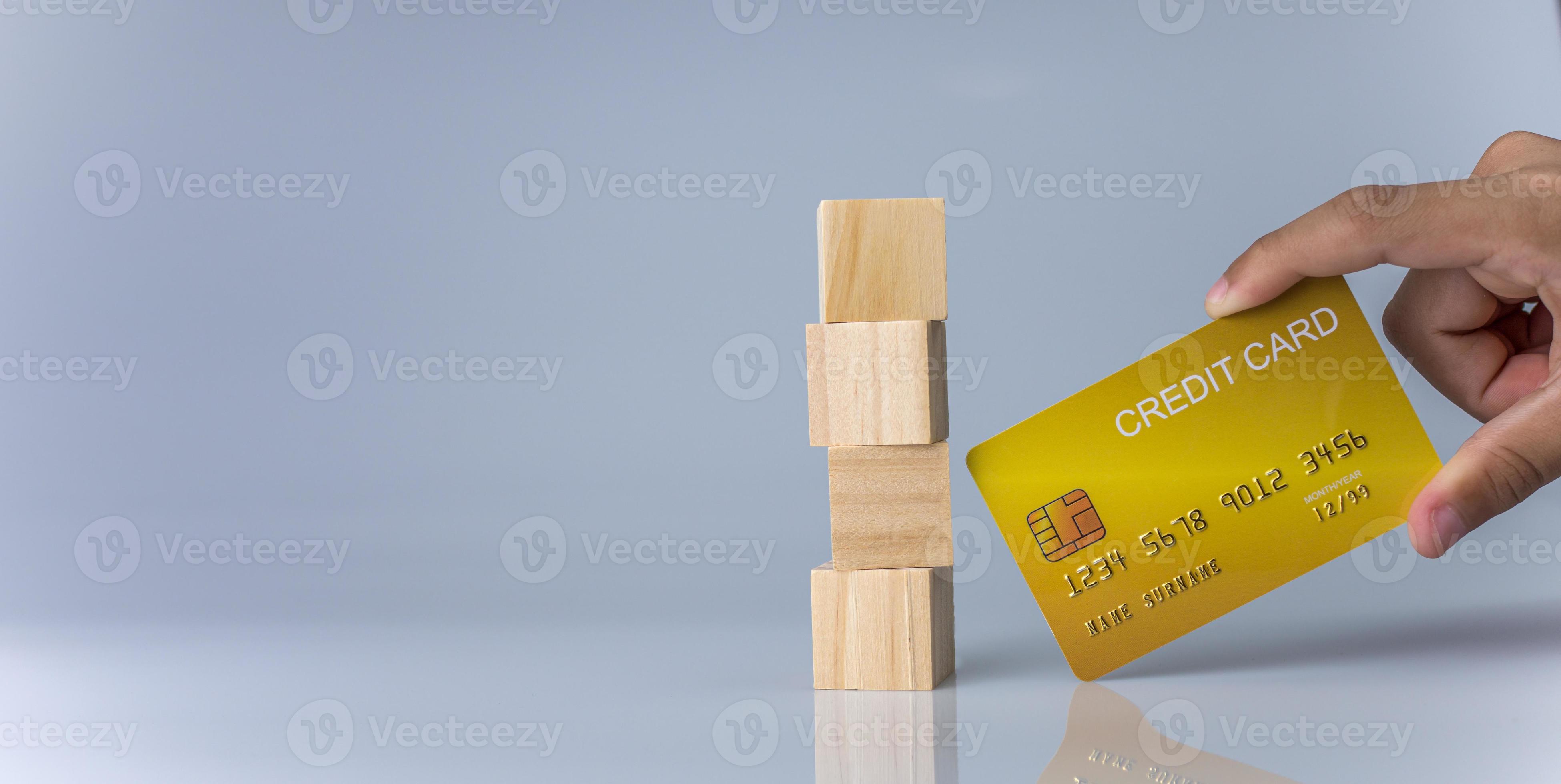Hands holding credit cards and wooden cube blocks stacked on top of