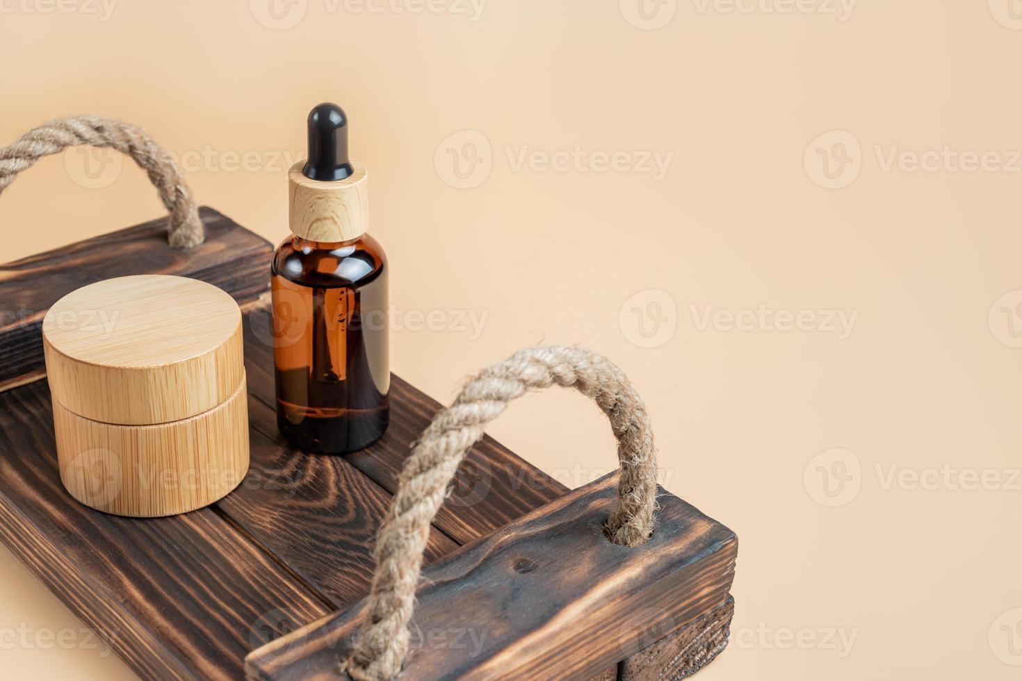 Cosmetics SPA branding mock-up. Dark glass cosmetic bottles and jars on wooden tray on beige background with copy space. Natural organic beauty product concept, Minimalism style photo
