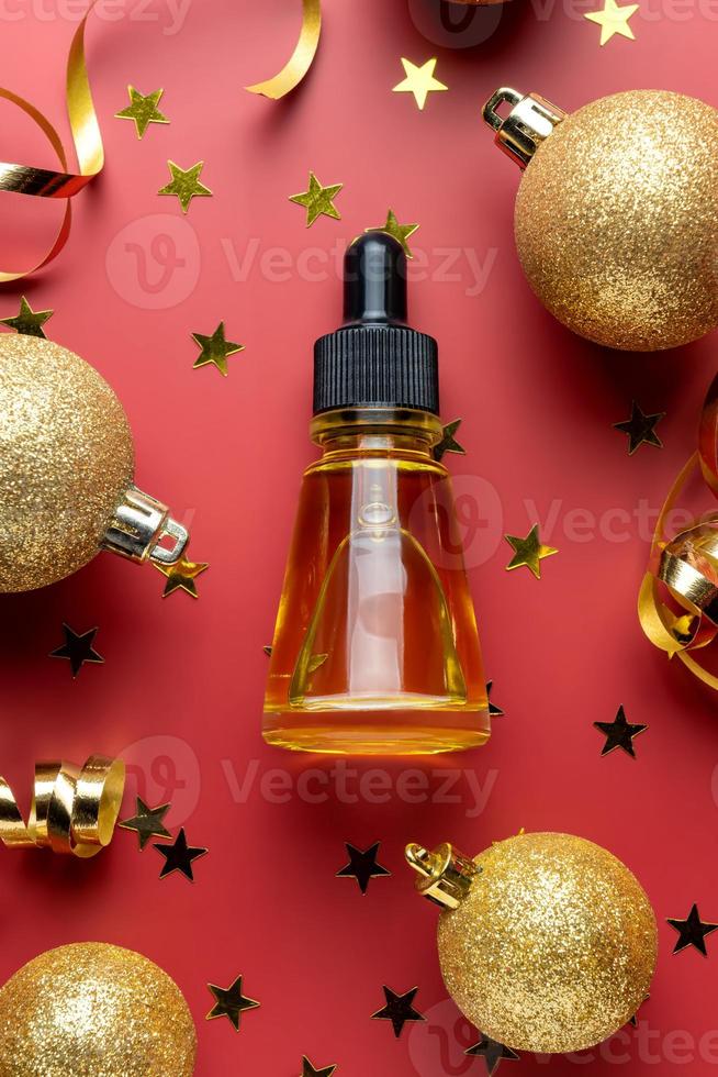 Top view of face essemtial oil with natural ingredients on red gitter background with streamers. New year or christmas gifts of skincare products and cosmetics. photo