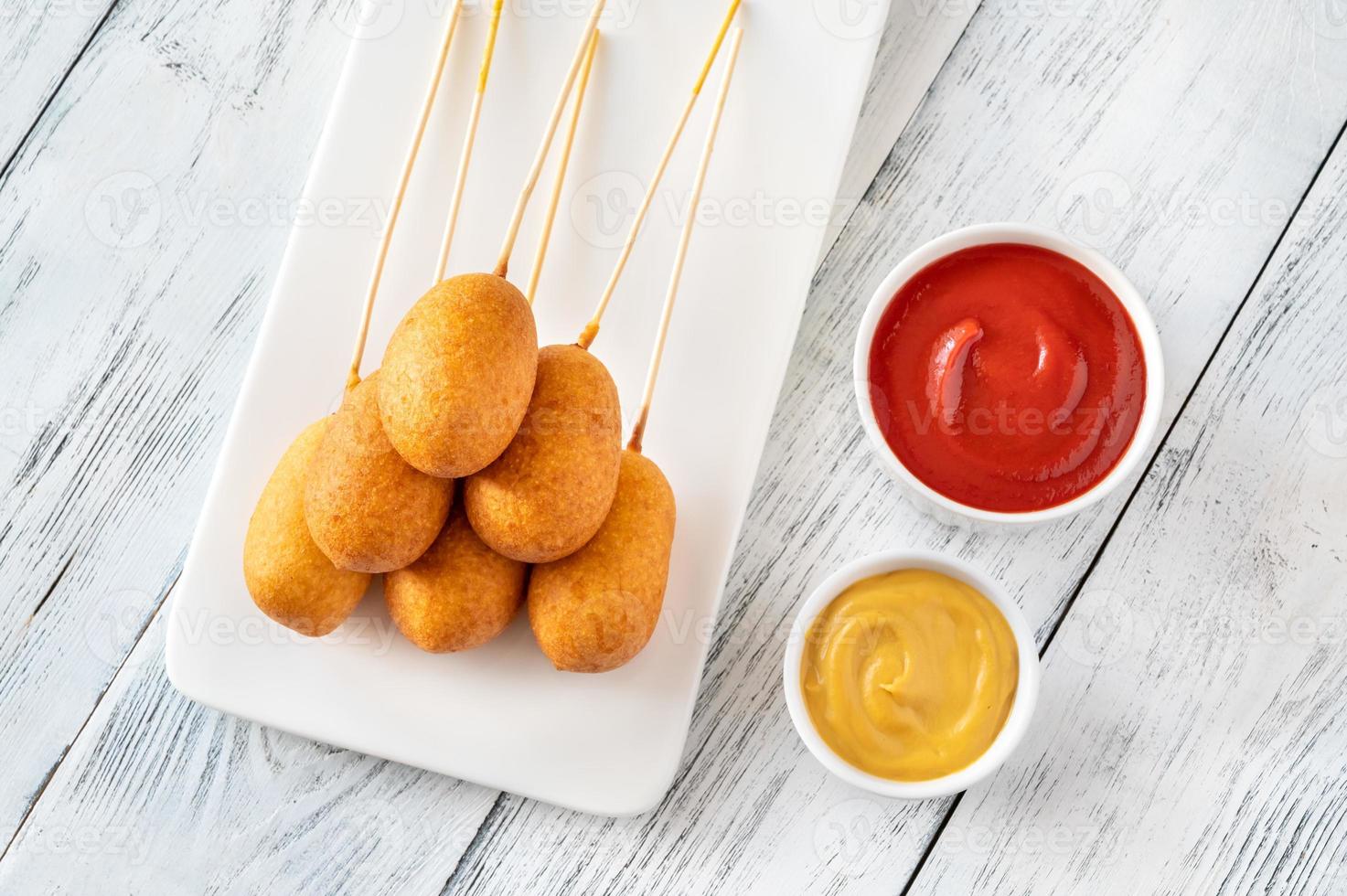 Corn dogs on white serving plate photo