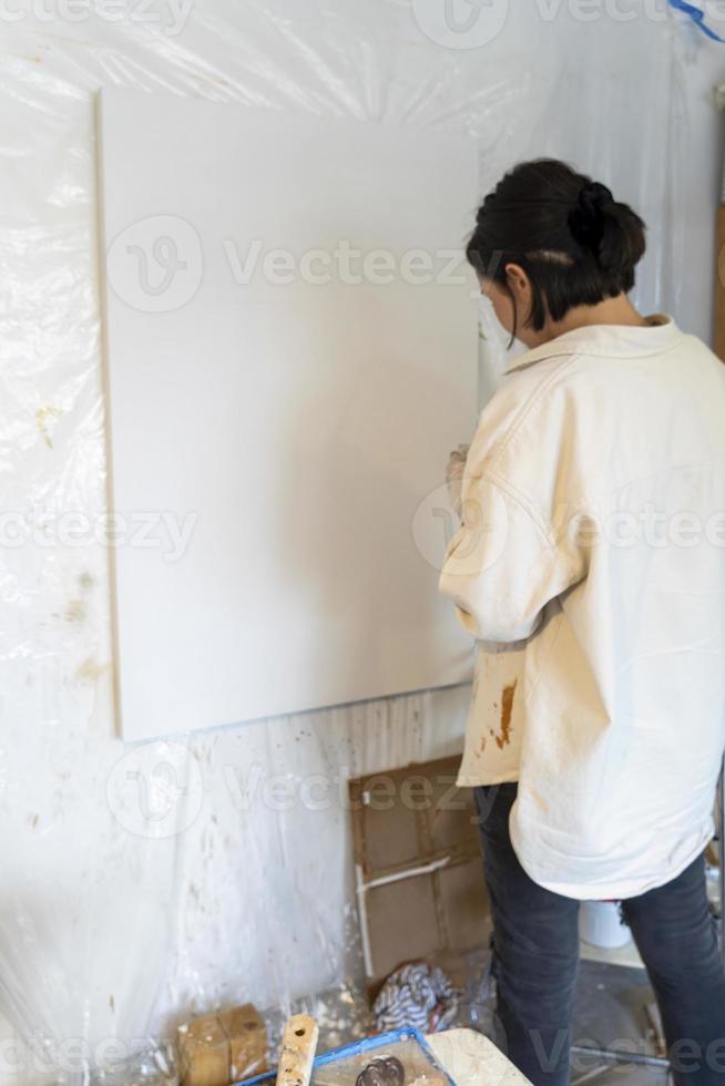 pintura sobre lienzo en blanco, mujer hispana con pinceles y pintura al óleo foto